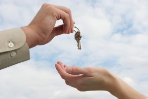A person handing over a key to another person.