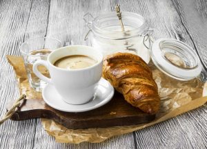 A cup of coffee and some croissants on a table.