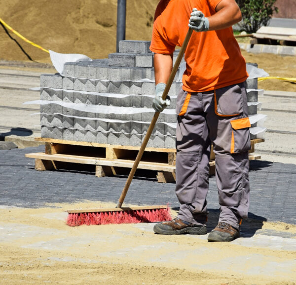 A man sweeping the ground with a broom.