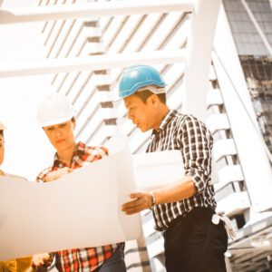 Three men in hard hats looking at a paper.