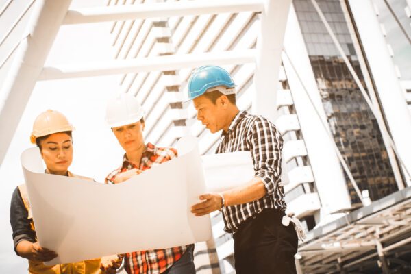 Three men in hard hats looking at a paper.