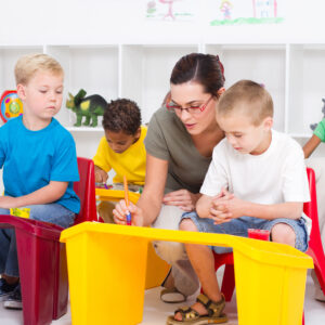 A woman sitting on top of two chairs next to children.