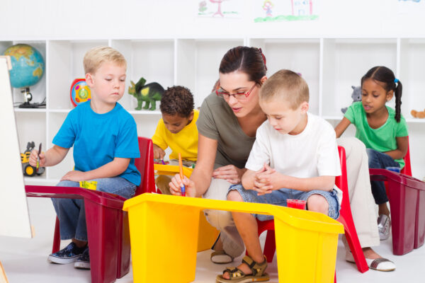 A woman sitting on top of two chairs next to children.