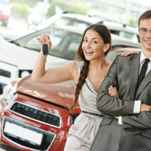 A woman holding up a car key next to a man.