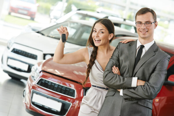 A woman holding up a car key next to a man.