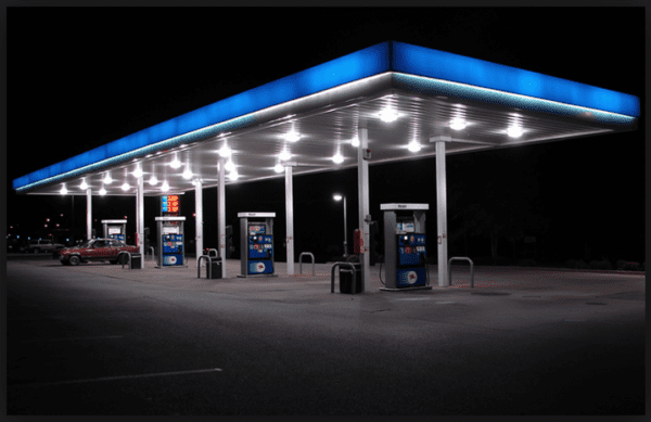 A gas station with many pumps at night.