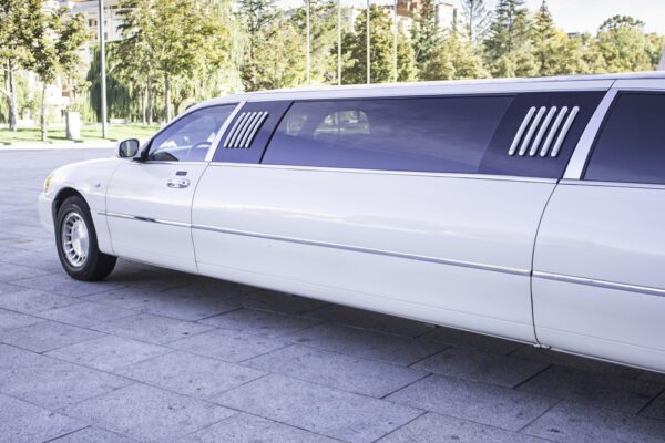 A white limo parked on the side of a road.