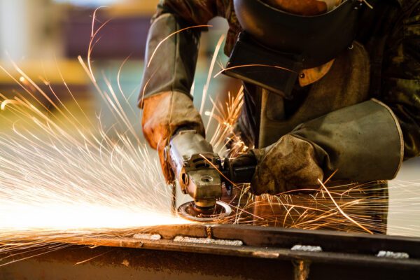 A person using an angle grinder to cut metal.