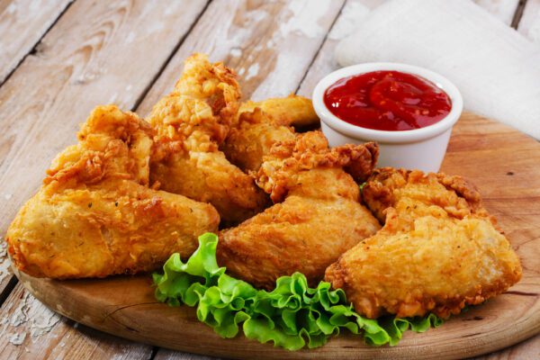 A wooden platter of fried chicken and ketchup.