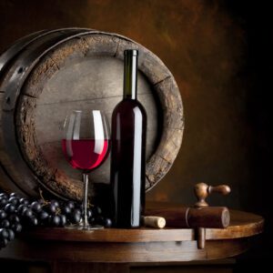 A wine glass and bottle on top of a barrel.