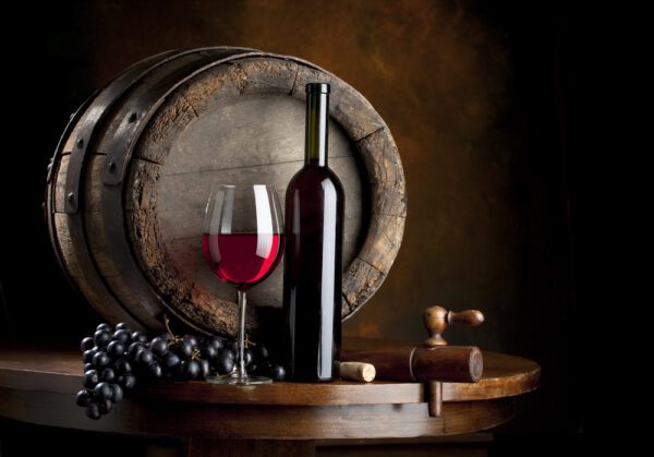 A wine glass and bottle on top of a barrel.