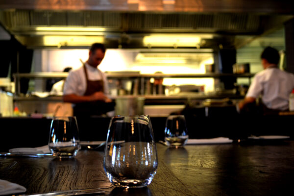 A person in a kitchen with some glasses on the table