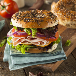 A sandwich with meat, lettuce and tomato on a bagel.