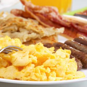 A plate of breakfast food with eggs, bacon and sausage.