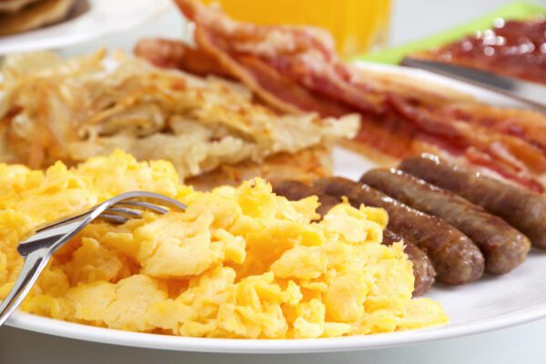 A plate of breakfast food with eggs, bacon and sausage.