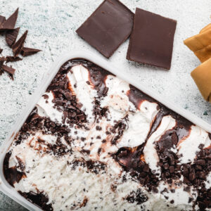 A white pan filled with chocolate cake and some pieces of chocolate.