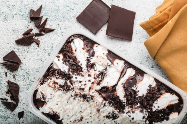 A white pan filled with chocolate cake and some pieces of chocolate.