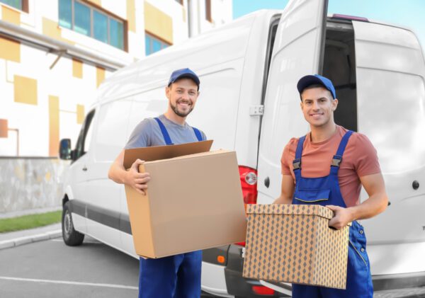 Two men holding boxes and a van