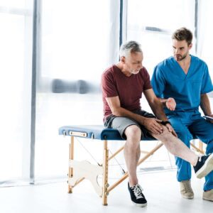 A man sitting on top of a table next to another person.