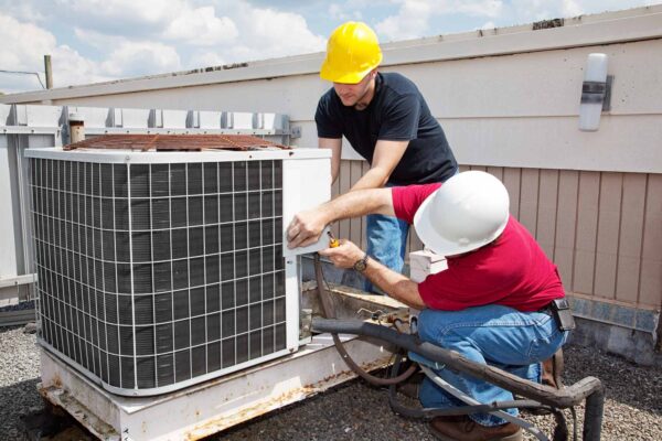 Two men working on an air conditioner unit.